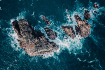 Aerial view a set of big rocks in the  sea with white split water