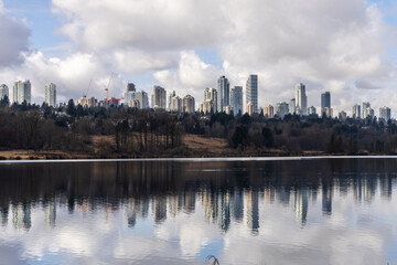Fototapeta premium Reflection of Burnaby Skyline Over Deer Lake Under Cloudy Sky