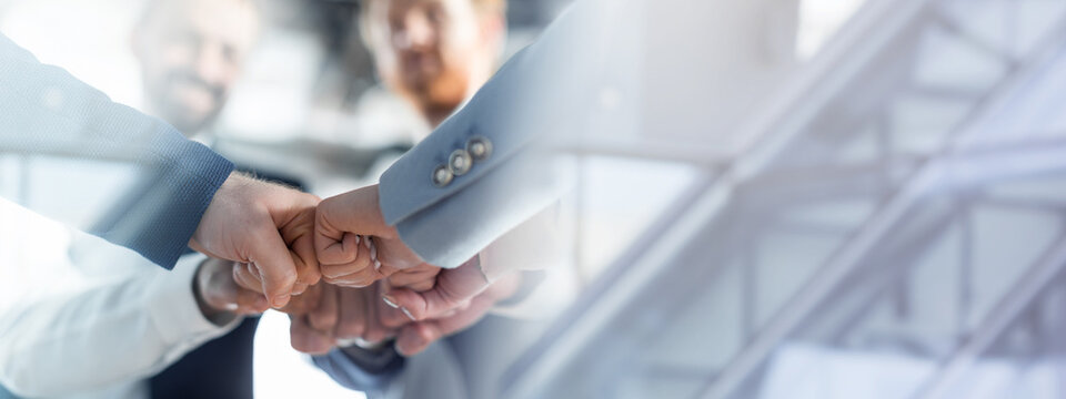Cropped of a business teams hands clasped together in a fist bump, showcasing their camaraderie and unity. The image captures the essence of teamwork and collaboration in a professional setting.