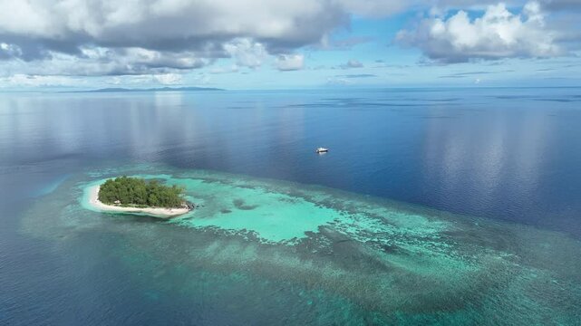 An idyllic, tropical island is surrounded by healthy coral reef in the Togian Islands of Indonesia. This equatorial area is part of the Coral Triangle and harbors incredible marine biodiversity.
