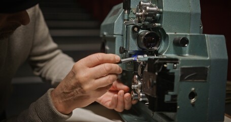 A dedicated craftsman meticulously working on the repair of a vintage film projector