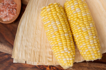 Two Fresh Corn on the Cob Resting on Husk with Himalayan Salt