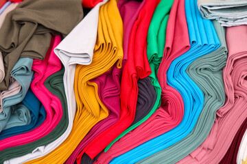 Colorful bolts of cloth arranged on a table are creating a vibrant display