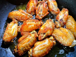 Frying chicken wings in pan, in door Chiangmai Thailand.