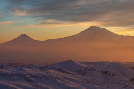 Mount Ararat (Masis), the national symbol of Armenia, seen during a cold winter sunset with a colorful sky. The snow-covered peak stands tall, located in present-day Turkey