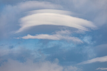 Lenticular clouds weather phenomenon over the landscapes of Syunik (Zangezur), Armenia. These unique cloud formations create a dramatic and atmospheric scene over rolling hills and open skies.
