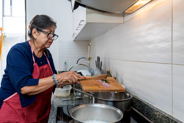 Senior latin woman preparing ingredients while cooking at home