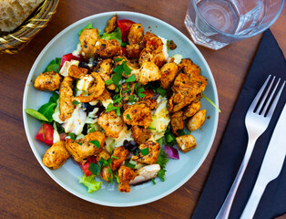 Traditional dish of American cuisine is a warm Caesar salad with fried chicken and champignons, cooked with the addition of ..fresh chopped tomatoes, lettuce, cheese and seasoned with sauce