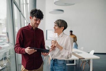 Business colleagues discussing work on digital tablet in modern office