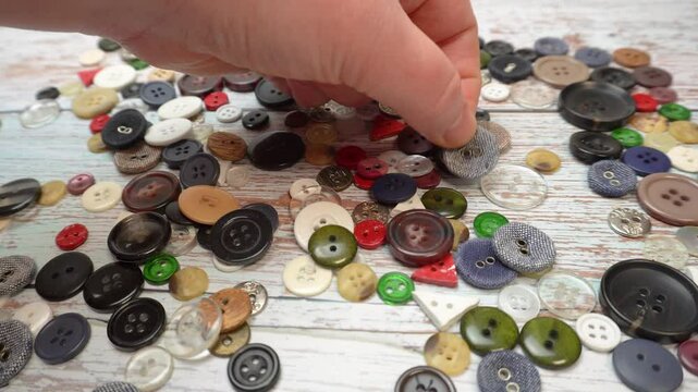 A collection of vintage buttons on a wooden surface. A variety of buttons of different shapes, colors and materials are scattered on the aged wooden surface.