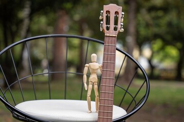 Articulated doll with a musical instrument. Doll on a chair. Articulated wooden doll