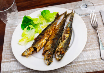 Just cooked fried sardines served on table in restaurant.