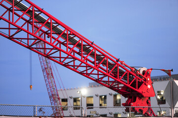Close-up of a red lattice boom crane at a data center construction site, showing steel framework,...