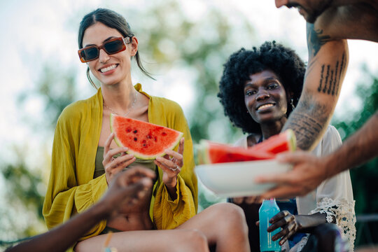 Friends eating watermelon slices at poolside summer party