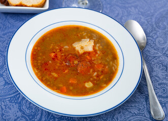 Lentil stew with chorizo, traditional Spanish dish, served on table in restaurant.