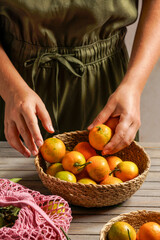 woman holding a rustic basket filled with fresh tangerines with leaves, creating a natural and organic feel