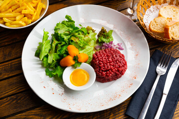 Tartar beef with a quail egg and arugula served on plate. Modern French cuisine
