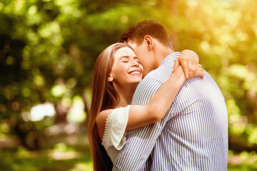 Fototapeta premium Tender couple embracing, bonding to each other at summer park on bright day. Blank space