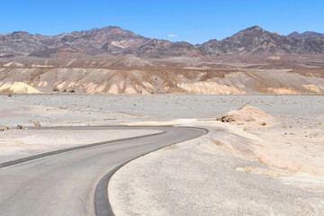 Road through a desert landscape with mountains in the background