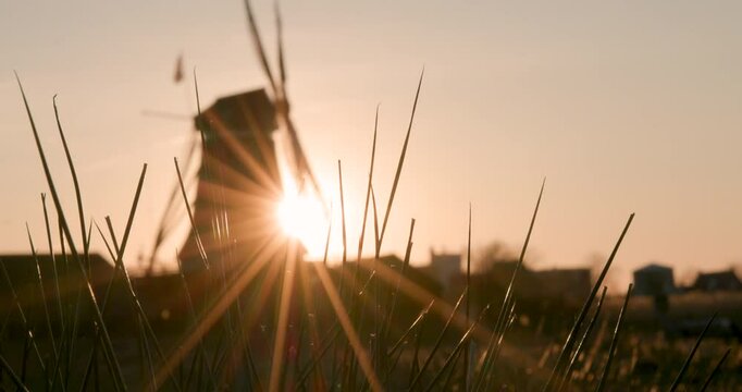 A scenic clip of a windmill behind some high grass at sunset.