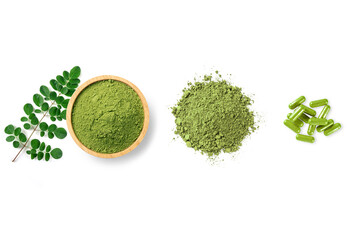 Moringa powder in wooden bowl with capsules and moringa leaves isolated on white background. top...
