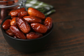 Tasty dried dates in bowl on wooden table, closeup. Space for text