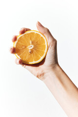 Hand holding a slice of orange on a white background, with the fruit split between fingers and palm