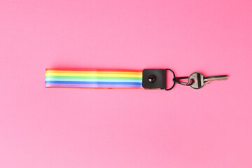 Key with keychain in LGBT colors on pink background, top view