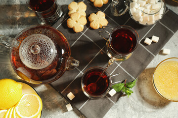Glasses of tea in metal holders served on grey textured table, flat lay