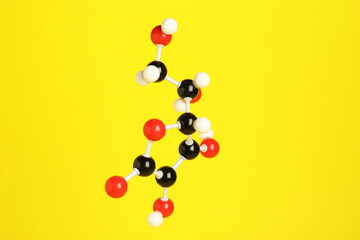 Molecule of vitamin C on yellow background. Chemical model