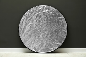 One light reflector near grey wall indoors. Photo studio equipment