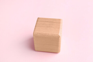 One blank wooden cube on pink background, closeup