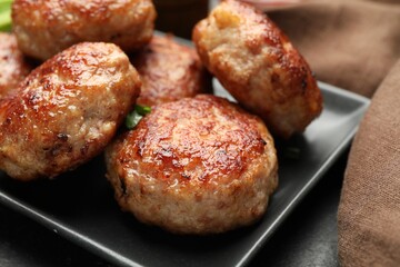Delicious roasted patties on black table, closeup