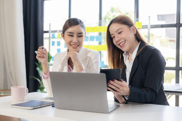 Two Asian women talk, consult, discuss work with presentation of new project idea, analyze business marketing plan.