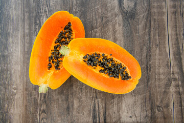 Papaya fruit on a dark wooden background. Slices of sweet papaya, Halved papayas