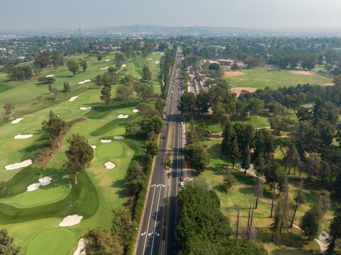 Aerial view of Hillcrest Country Club golf course and a road with cars in Los Angeles, California, USA. The photo shows the urban landscape and recreational activities. Los Angeles, California, USA