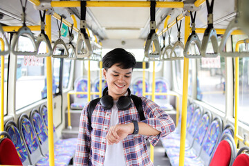 Positive College Student Asian Man Checking His Smart Watch While Standing On Public Transport