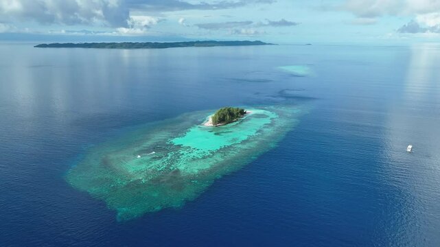 An idyllic, tropical island is surrounded by healthy coral reef in the Togian Islands of Indonesia. This equatorial area is part of the Coral Triangle and harbors incredible marine biodiversity.