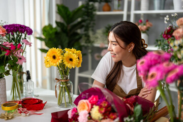 Asian young florist girl completing beautiful bouquet in flower shop. 