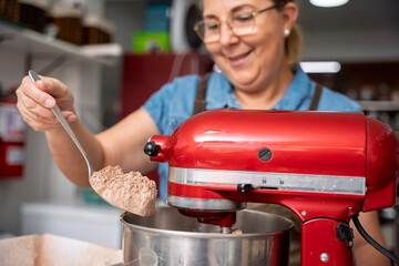 Pastry chef adding cocoa powder to stand mixer, preparing dessert