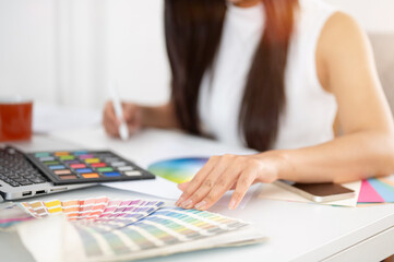 Close up of a hand touching on printed color chart and other hand holding a stylus drawing on...