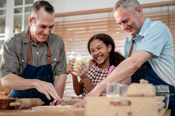 Caucasian senior gay couple baking bakery with adopted daughter in house.