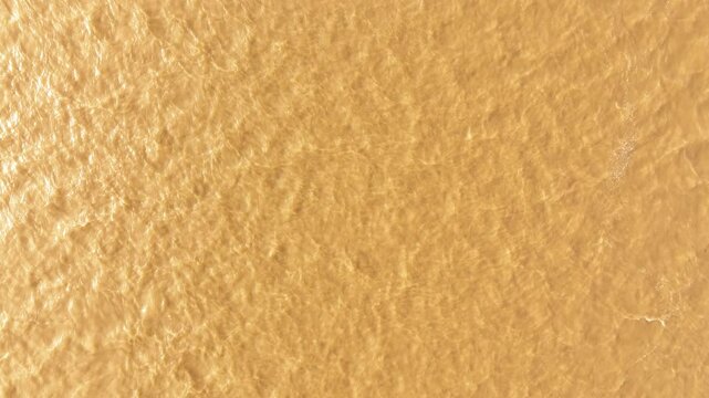 Bird's eye view of brown muddy water in the Mississippi River with the sun shining bright.