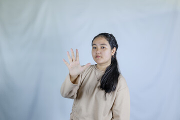A young woman wearing a gray t-shirt with a shocked expression says stop. Advertising theme concept studio photo