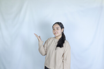 a young girl wearing a gray t-shirt pointing to a product. advertising theme concept studio photo