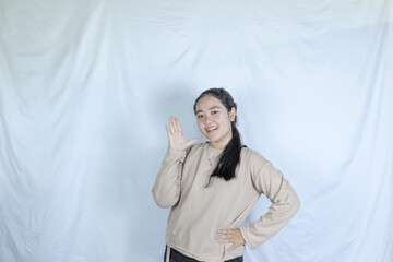 a young girl wearing a gray t-shirt raises her hand saying hi. photo studio advertising theme concept