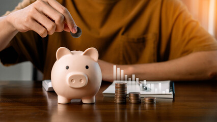 Concepts of saving money and financial planning.  A person is putting coins into a piggy bank....