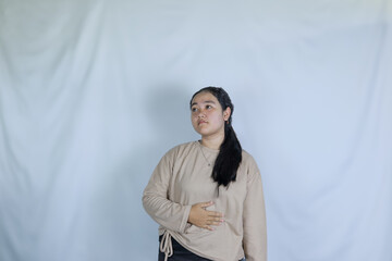 a young girl wearing a gray t-shirt with a hungry expression with her hands holding her stomach. advertising theme concept studio photo