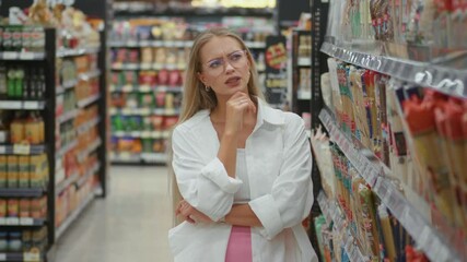 Woman in supermarket facing confusion over endless product options, confusion rising with each aisle, confusion prompting careful comparison, ideal for illustrating consumer dilemmas.