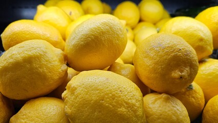 a pile of fresh yellow lemons on the shelf in a supermarket